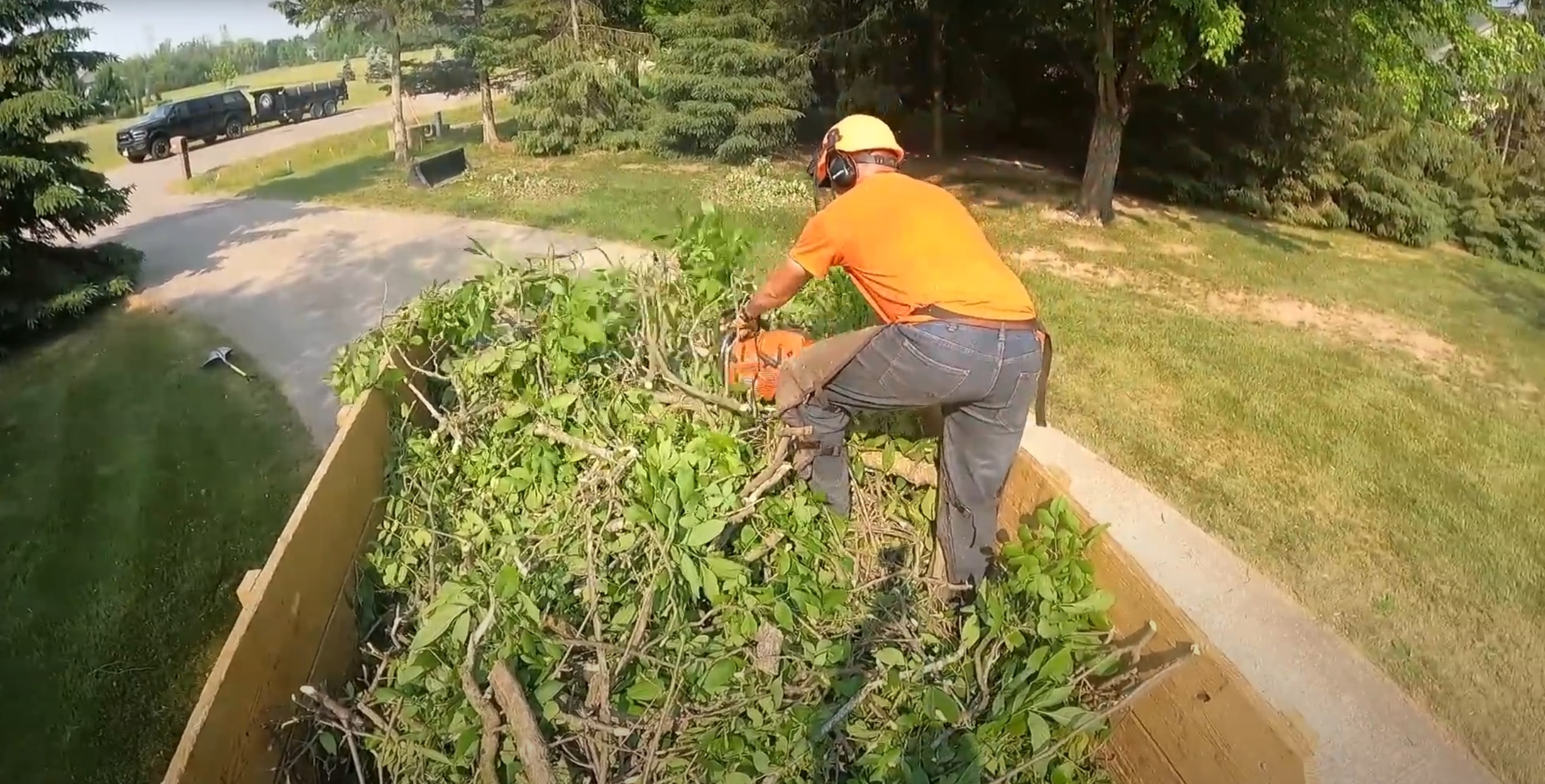 Tree service worker with chainsaw clearing brush and tree debris from a large lot in Texas